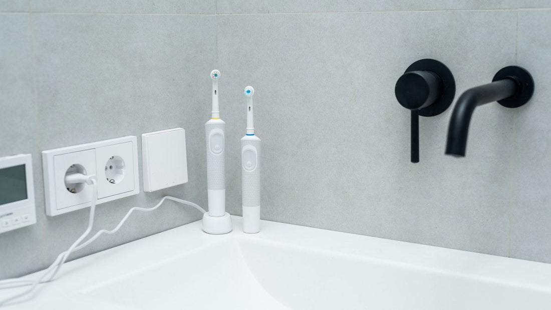 Deux brosses à dents électriques blanches posées sur un lavabo blanc, photo d’illustration générique.