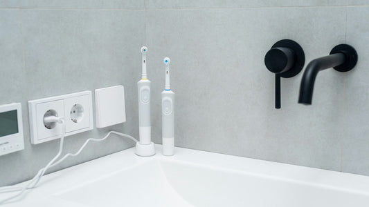 Deux brosses à dents électriques blanches posées sur un lavabo blanc, photo d’illustration générique.