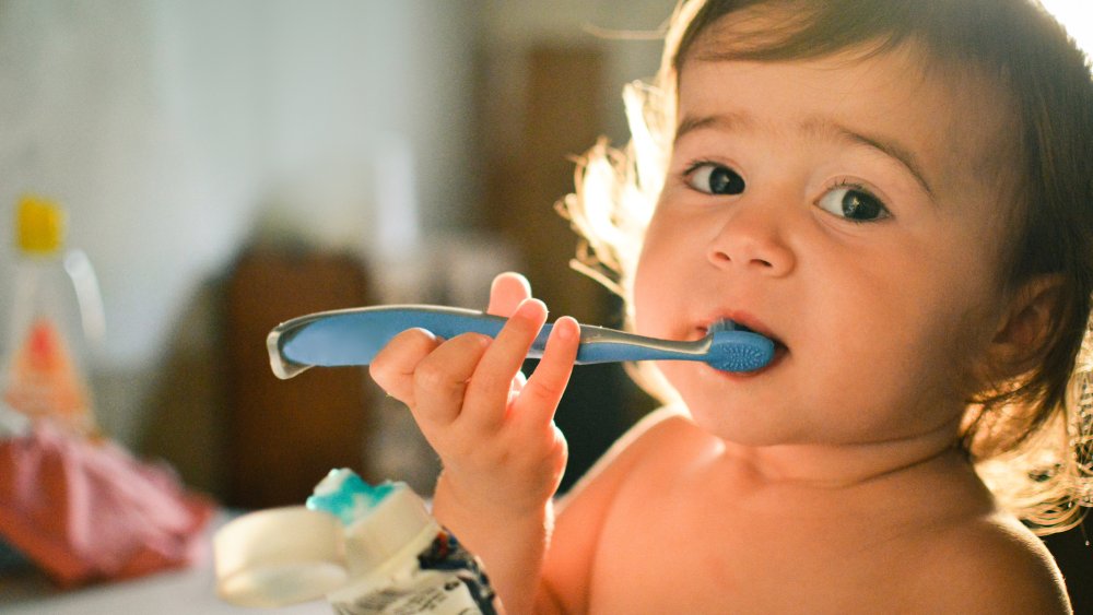 Parent brossant doucement les premières dents de son bébé