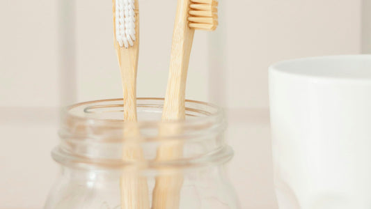 Deux brosses à dents en bambou dans un bocal en verre, illustration générique du rangement de brosses personnelles.